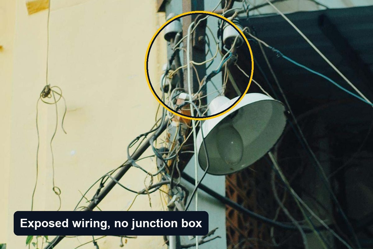 Exposed electrical wiring and an open junction box on an exterior wall