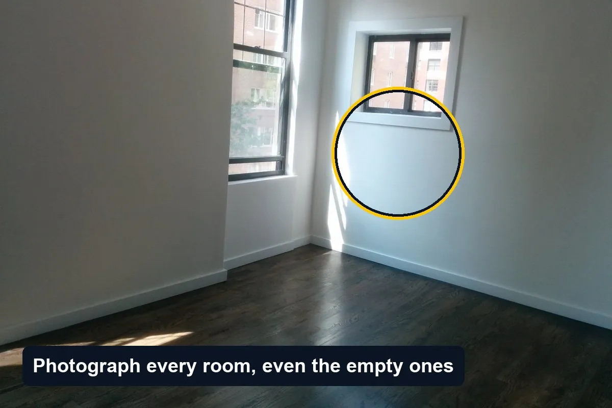 An empty apartment room with white walls, a dark wooden floor and two windows, one wall circled, with the label Photograph every room, even the empty ones