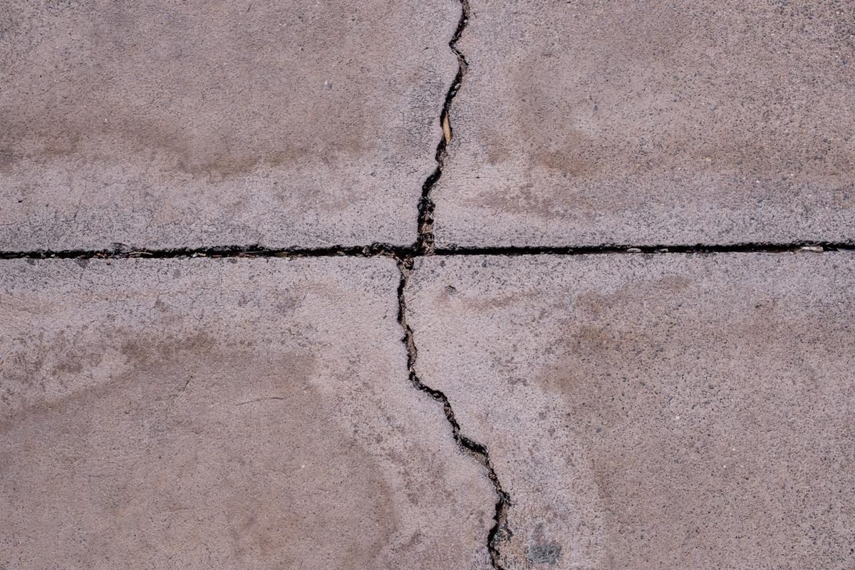 Crack running through a concrete slab and across a control joint, seen from above