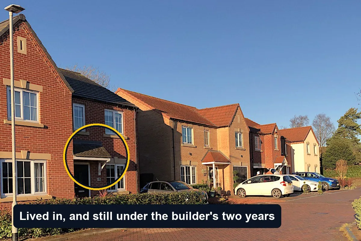 A street of recently completed brick houses in England with cars parked outside; the front door of one house is circled with the label Lived in, and still under the builder's two years