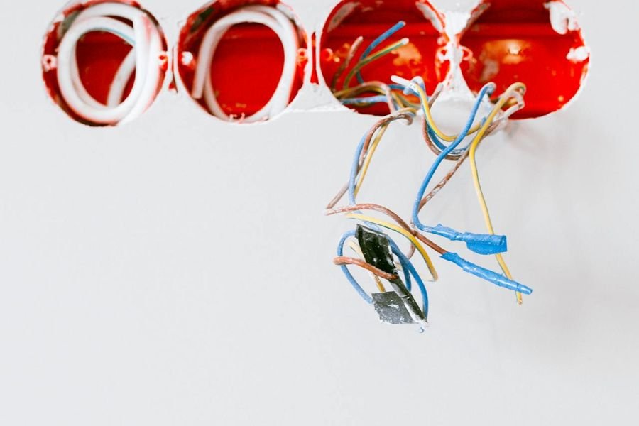 Four red back boxes cut into a white plastered wall with cable cores hanging out, before accessories were fitted