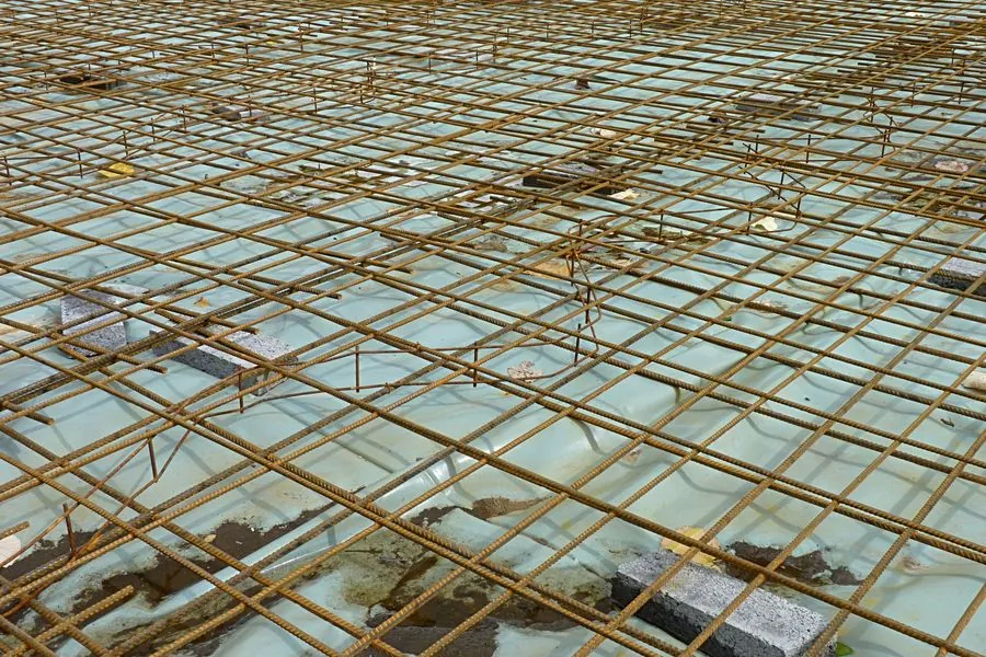 A reinforcement mat of ribbed steel bars laid over a slab before concrete is poured