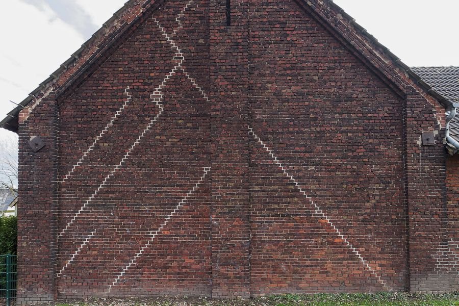Brick gable wall with several long diagonal stepped cracks that have been repointed in pale mortar